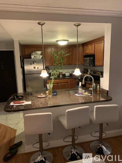 A kitchen with a granite countertop and white bar stools.
