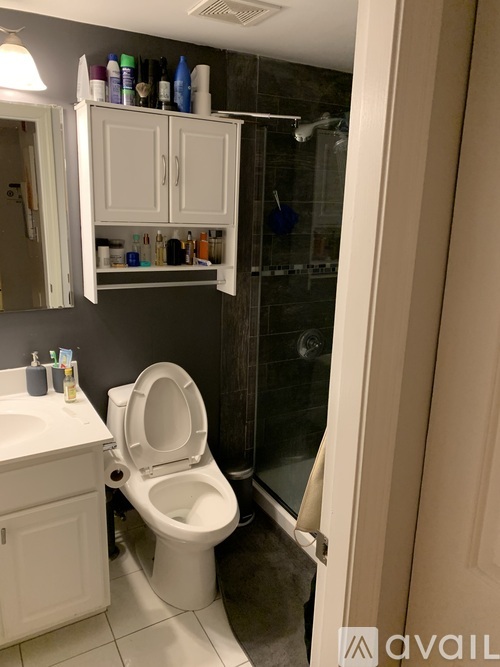 A white toilet in a bathroom with a cabinet above it.