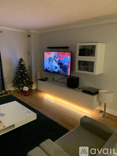 A living room with a television, a Christmas tree, and a grey sofa.