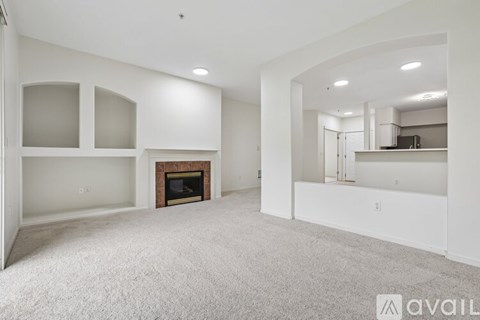 A spacious living room with a fireplace and a carpeted floor.