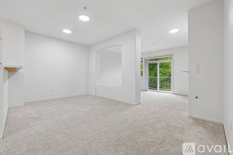 A spacious, empty room with a carpeted floor and white walls.