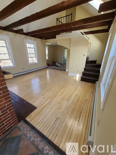 A large open room with wooden floors and a staircase.
