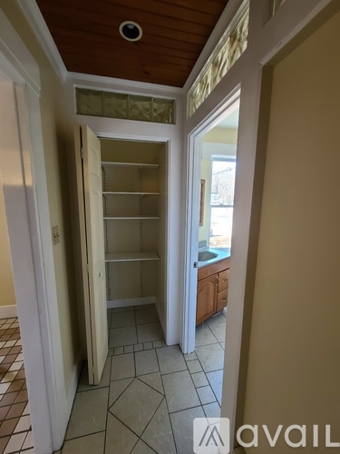 A room with a pantry and a kitchen in the background.
