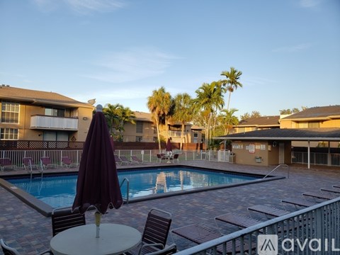 A pool area with a table and chairs and a pool umbrella.