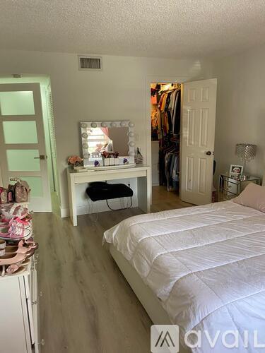 A bedroom with a white bed and a vanity table with a mirror.
