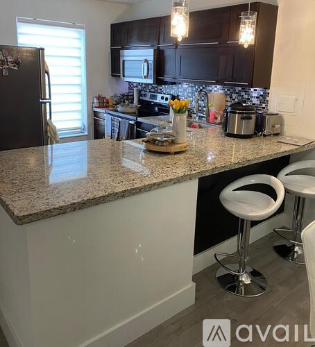 A kitchen with granite countertops and white stools.