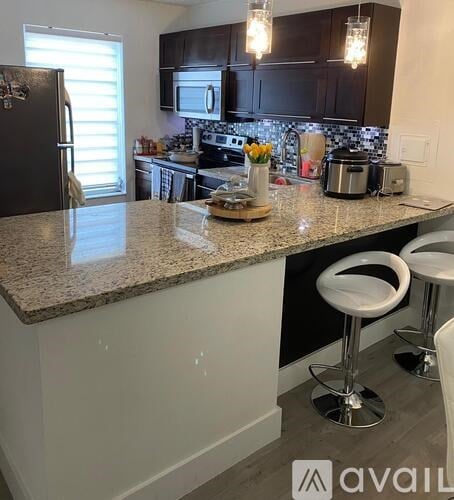 A kitchen with granite countertops and white stools.