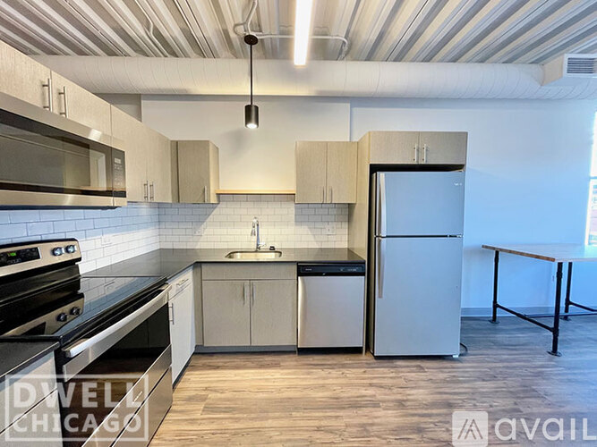 A kitchen with a stove top oven, microwave, refrigerator, and sink.