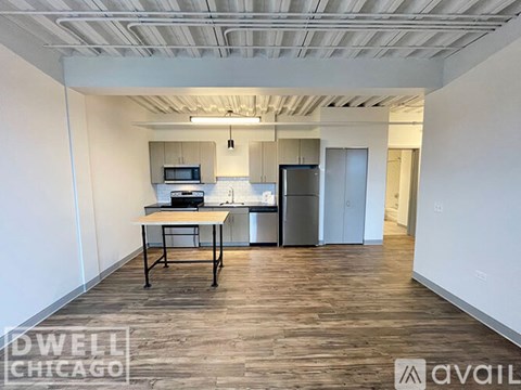 A kitchen area with a table and a refrigerator in a room with wooden flooring.