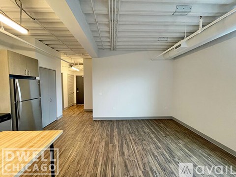 A room with wooden flooring and a stainless steel refrigerator.