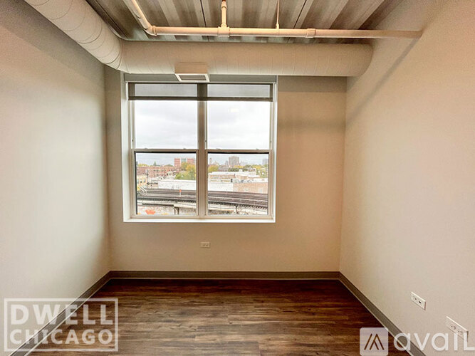 A room with a large window overlooking a cityscape is available for rent.