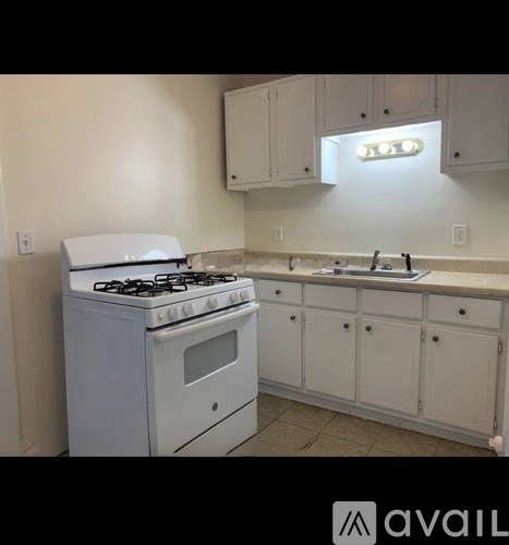 A white gas stove in a kitchen with white cabinets.