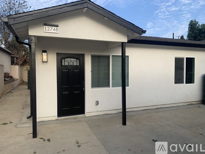 A white house with black door and windows is for sale.