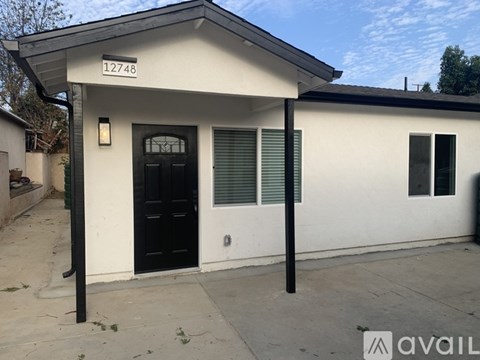A white house with black door and windows is for sale.