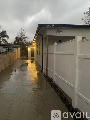 A wet walkway leads to a building with the number 12746 on it.