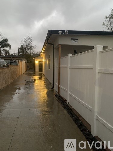 A wet walkway leads to a building with the number 12746 on it.