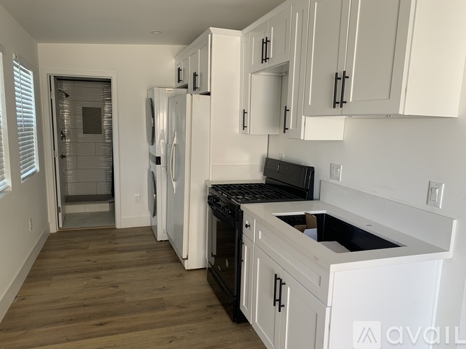 A kitchen with white cabinets and black appliances.