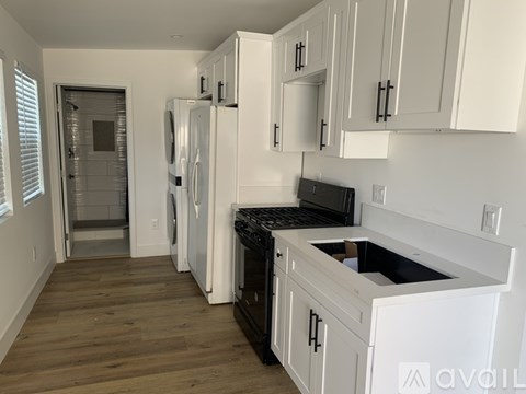 A kitchen with white cabinets and black appliances.