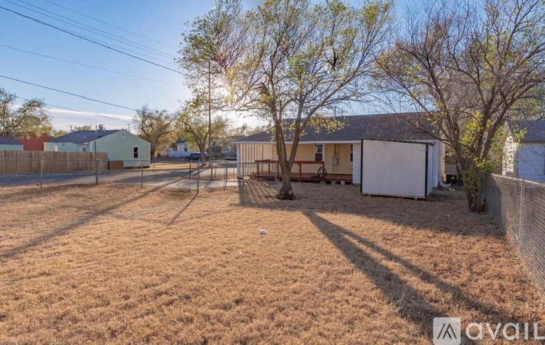 A backyard with a fence, a tree, and a shed.