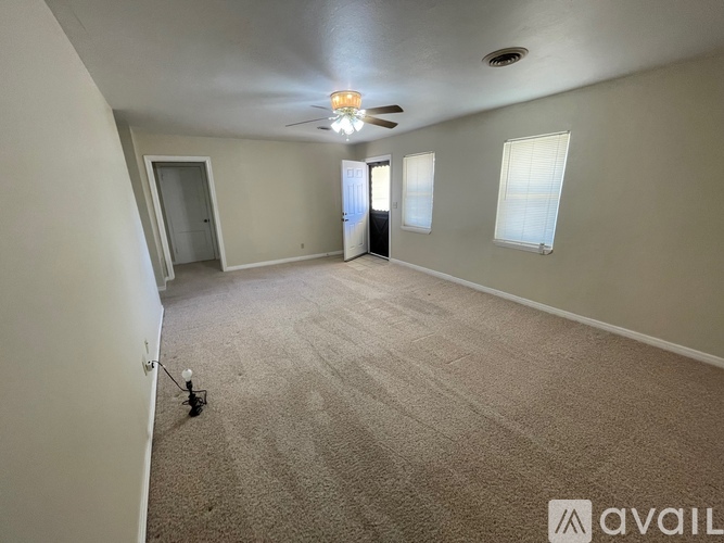 A spacious room with a carpeted floor and a ceiling fan.