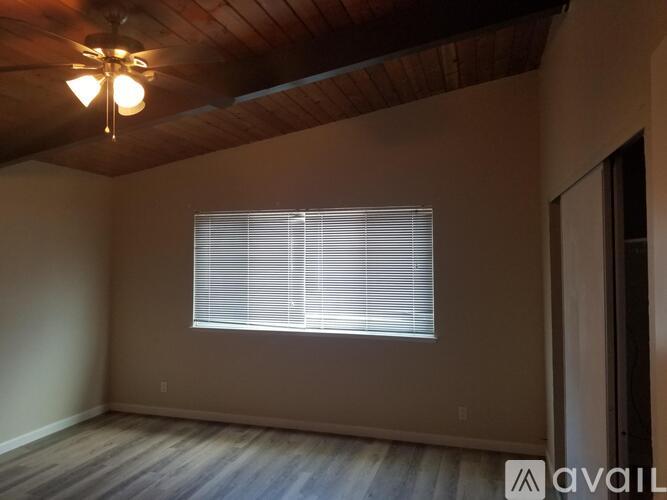 A room with a window covered by blinds and a wooden ceiling.