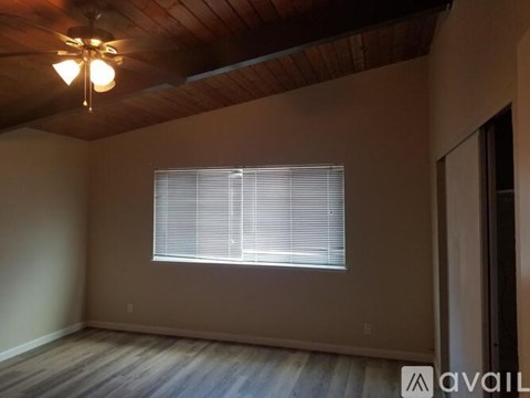 A room with a window covered by blinds and a wooden ceiling.