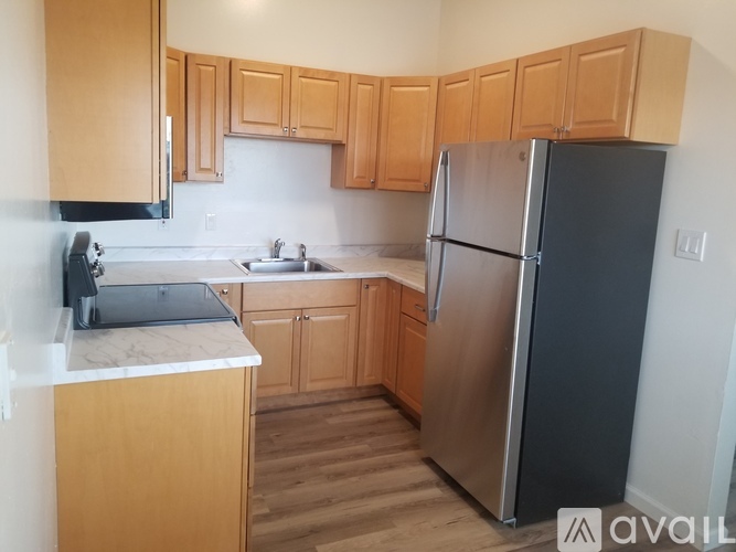 A kitchen with wooden cabinets and a black refrigerator.