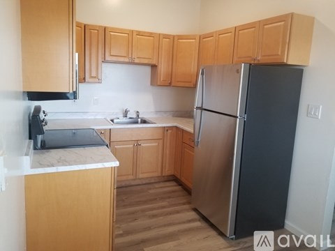 A kitchen with wooden cabinets and a black refrigerator.