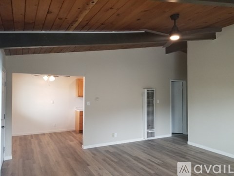 A spacious room with wooden floors and a ceiling fan.