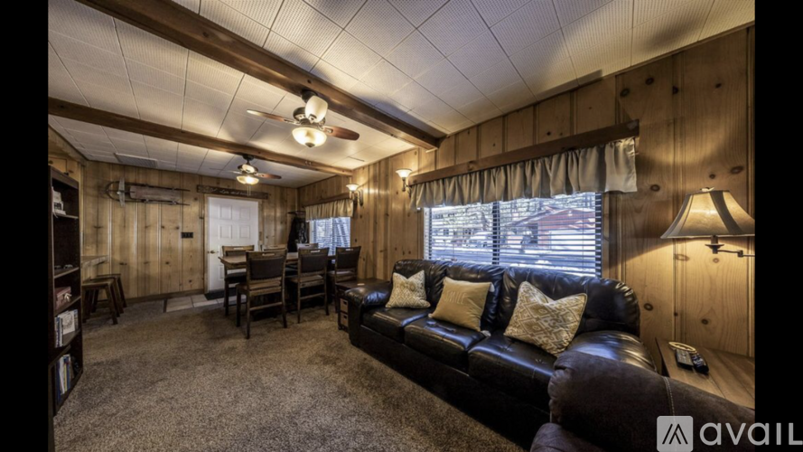A living room with a black couch and a ceiling fan.