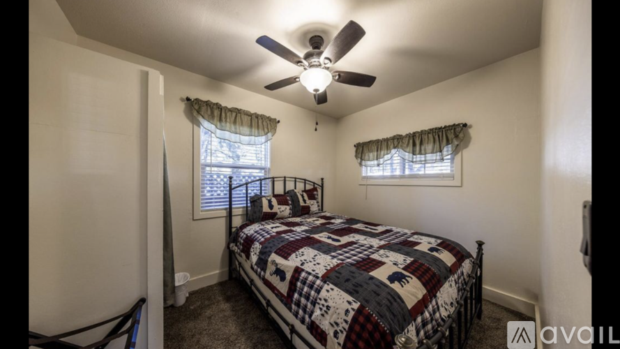 A bedroom with a bed, window, and ceiling fan.