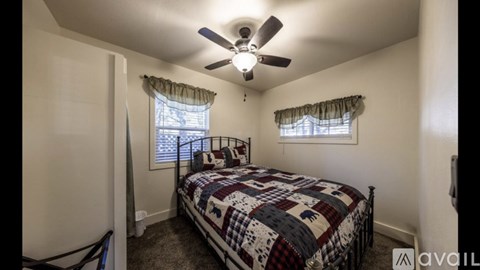 A bedroom with a bed, window, and ceiling fan.
