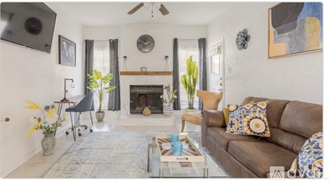 A living room with a fireplace, couch, and plants.