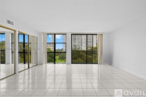 A spacious room with tiled flooring and sliding glass doors leading to a balcony.
