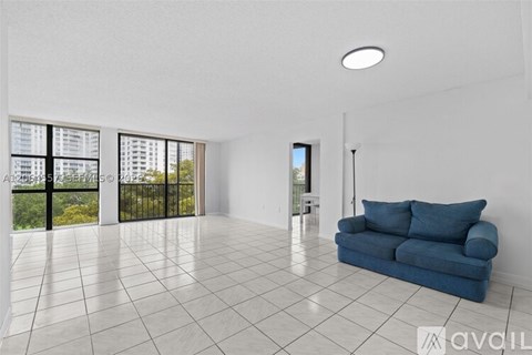 A spacious living room with a blue sofa and a view of a building outside the window.