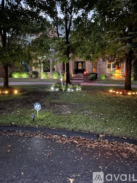 A blue sign with a white arrow pointing to the right is in the foreground of a residential street at night.