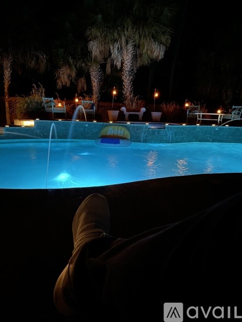 A person's feet in brown boots are in the foreground of a pool at night.