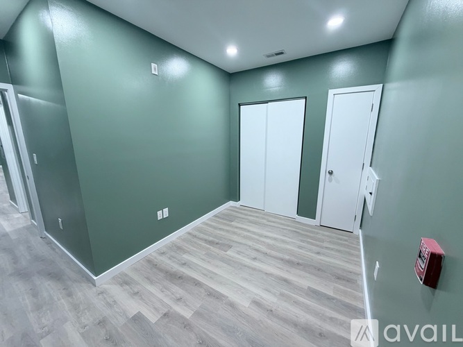 A room with green walls and wooden flooring with three doors.
