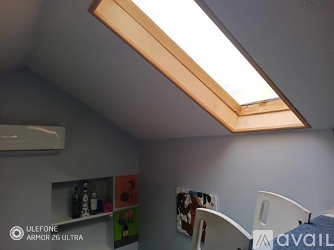 A room with a skylight and a shelf with various items on it.