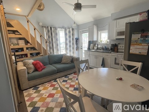 A living room with a couch, a table, and a fan.