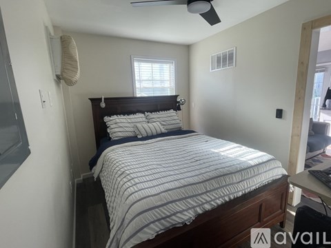 A bedroom with a bed, a ceiling fan, and a window.
