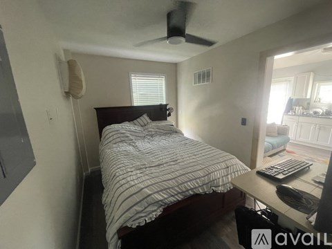 A bedroom with a bed, desk, and window.