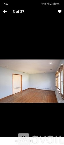 A room with wooden flooring and a window on the right side.