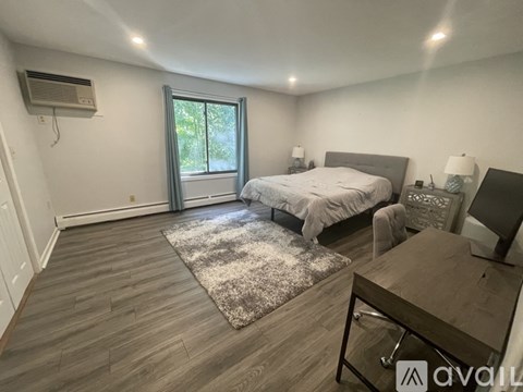 A bedroom with a bed, nightstand, and window.