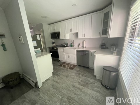 A kitchen with white cabinets and a grey floor.