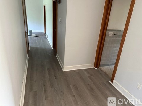 A long hallway with wood floors and white walls.