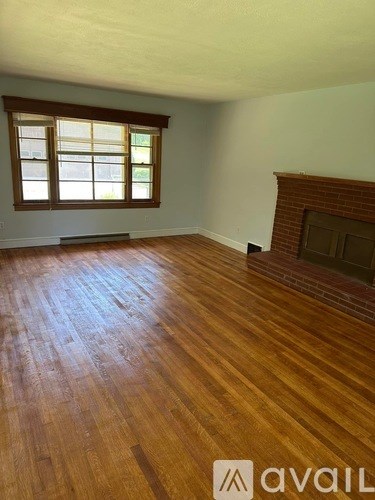 A room with wooden flooring and a fireplace.
