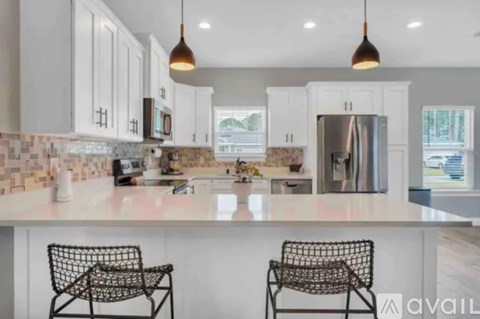 A kitchen with white cabinets and a marble countertop.