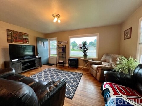 A living room with a black leather couch and a television.