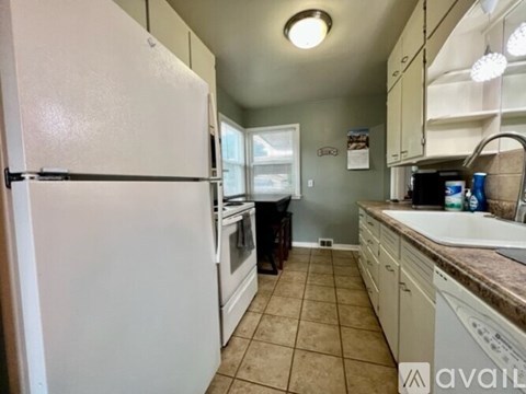 A kitchen with a white refrigerator and brown countertops.